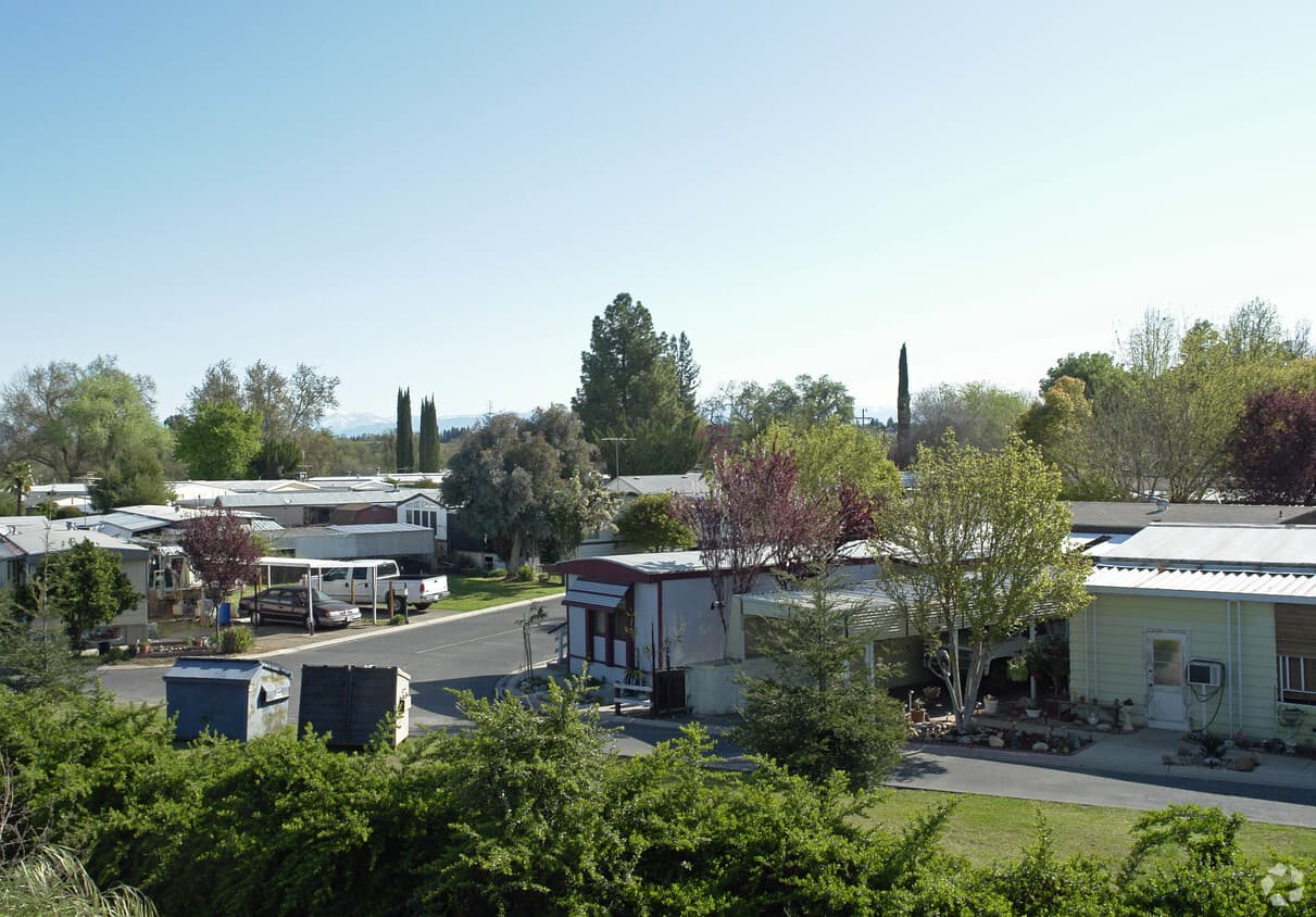 Woodward Bluffs Mobile Home Park on a sunny day, with tree-lined streets and mountains in the distance
